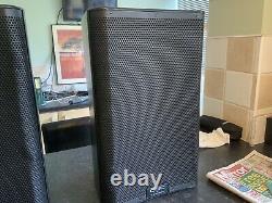 A Pair Of QSC K10.2 Powered Speakers Inc Tote Bags And Mains leads